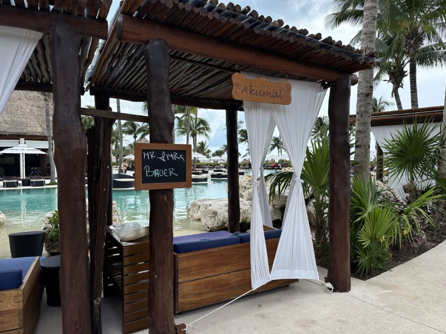 A cabana with wooden posts and room, covering a blue lounger. 